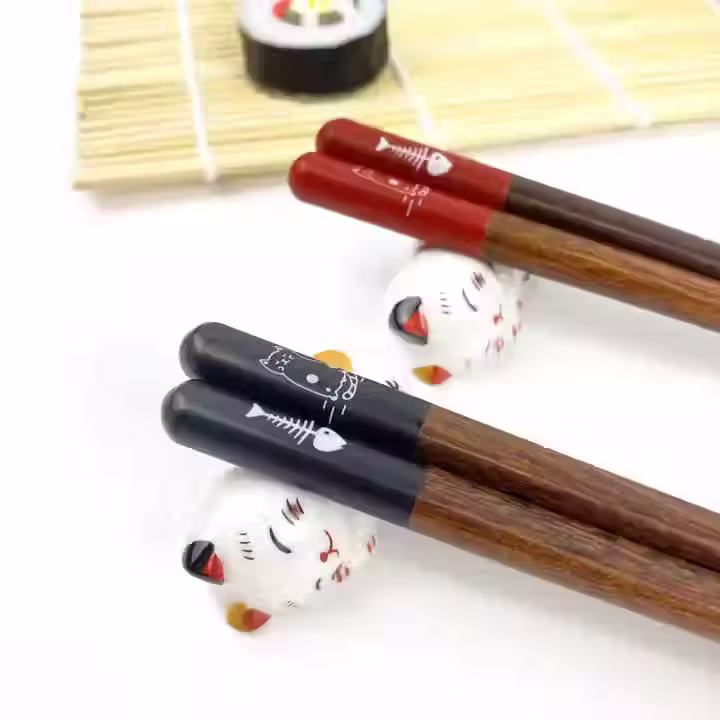 two chopsticks on ceramic white cat rests
