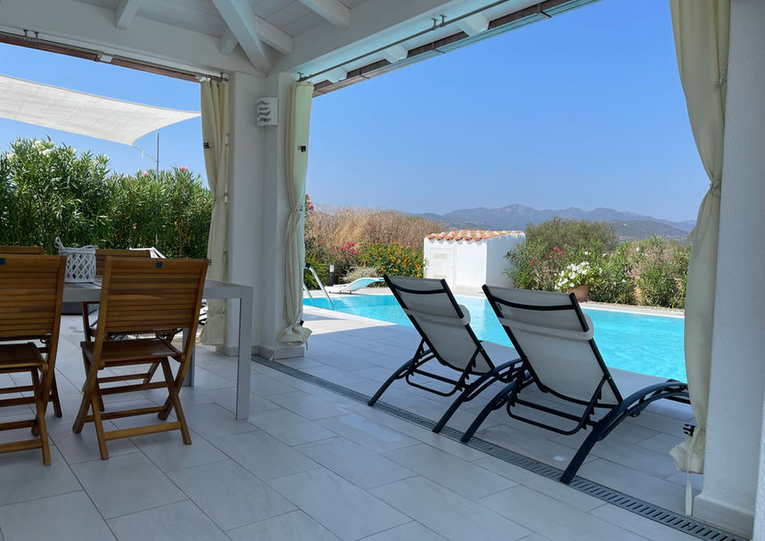 Outdoor wooden dining table on covered patio – Villa Anna in Budoni