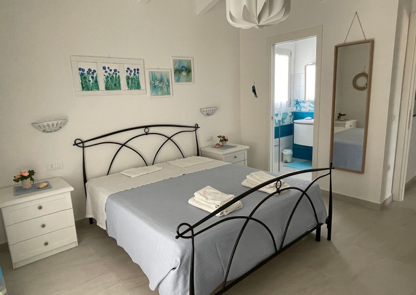 Master bedroom at Villa Agata, featuring a large bed and marine-style artwork for a peaceful rest.