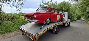 A black car on a vehicle trading service truck.