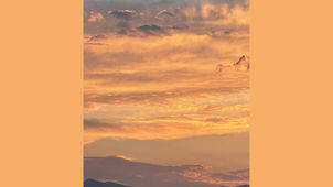 A yellow and orange sunset over mountains in the distance