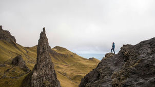 A person standing on rock hill with barren yellow hills in distance