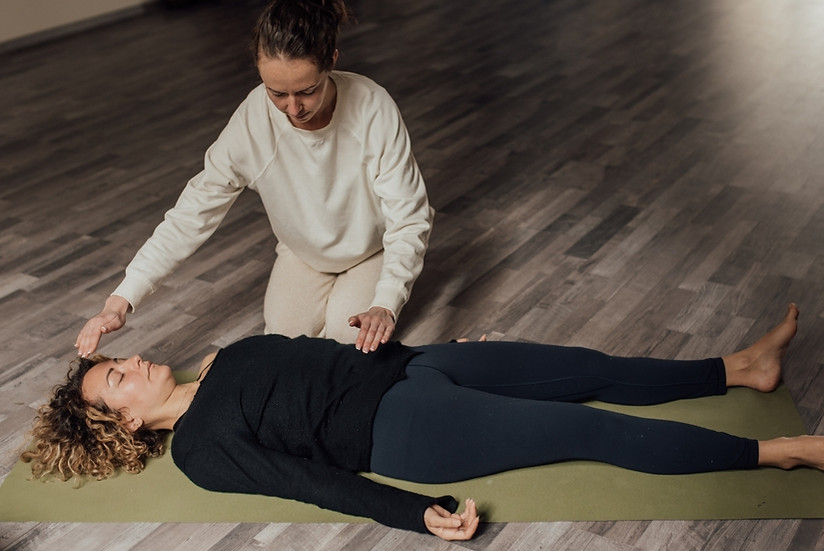 Yerde uzanan kişiye bütünsel enerji şifası ve reiki uygulaması