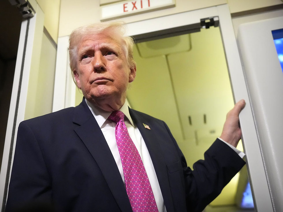 **Caption:**
"We are very, very prepared." President Trump, with a serious and focused expression, addresses questions from reporters on Air Force One regarding the U.S. response to recent actions by Iran. This image captures a moment of executive communication during the height of the 2019-2020 conflict with Iran. (Reference file: Trump on Airforce one takes Questions.jpg)
**Alt Text:**
A low-angle medium close-up shot of Donald Trump, in a dark navy suit and patterned pink tie, standing with a stern, focused expression near an aircraft exit door marked "EXIT." His left hand rests on the frame. His intense gaze is directed slightly upward and away, as if looking at a questioner or processing information. He is on Air Force One, speaking to the press about the Iran conflict.