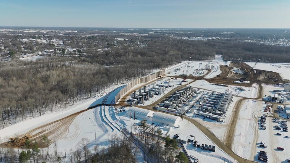 Aerial view of xAI's industrial gas turbine power plant site in Southaven, Mississippi. Rows of large white and gray turbines, construction cranes, equipment, and cleared land are visible, with a forested background and distant urban area.