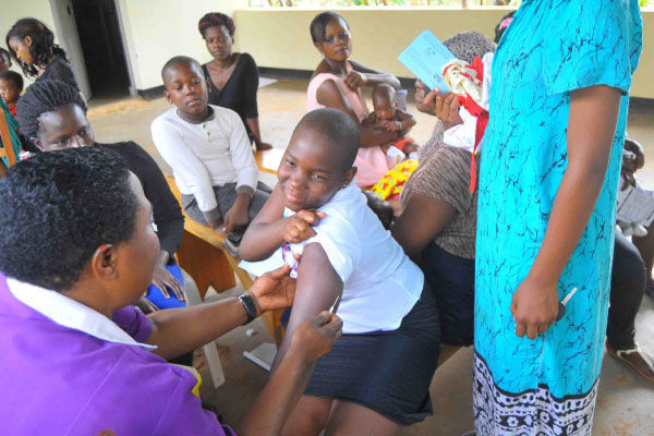 A health worker immunizes a girl against cervical cancer during a health campaign in December 2017, A health worker immunizes a primary school girl against cervical cancer, A health worker injects a HPV vaccine into the upper arm of a school girl in central Uganda, cervical cancer injection