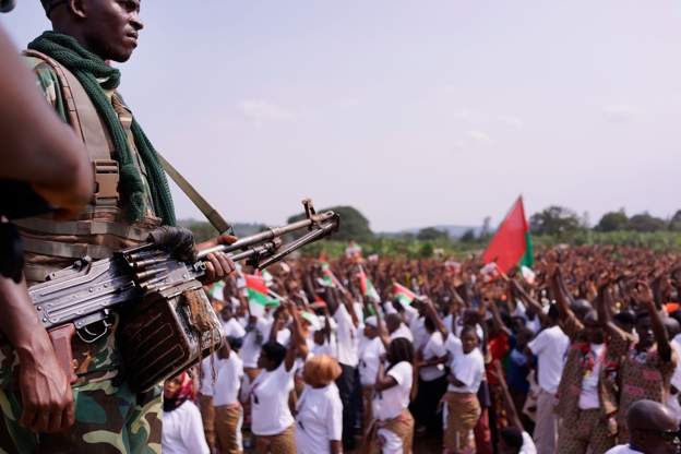 A soldier watches over a crowd of supporters at a political rally in Burundi