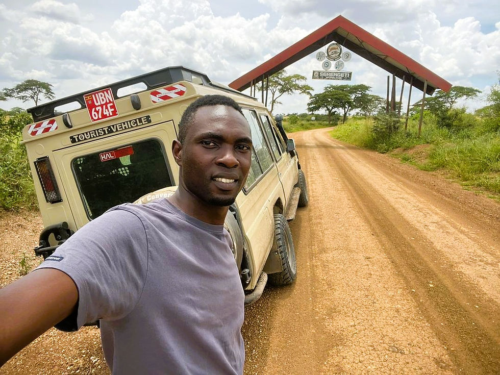 Narcis Tumwiine, tour director for Gone Wild Safaris, takes a selfie at the entrance gate of Serengeti National Park, Tanzania, highlighting East African tourism adventures. Photo credit: Gone Wild Safaris.