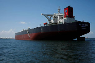 Large ship "Pu Tuo San" on calm sea, under clear blue sky. Red and black hull with industrial background.