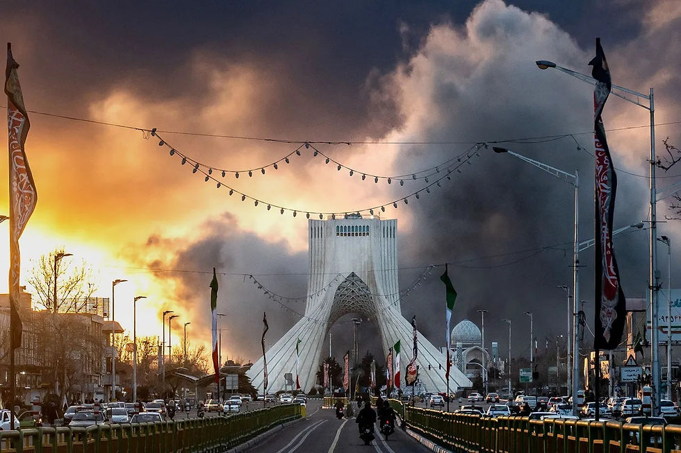 Iranian capital city Tehran with heavy smoke rising from explosions near a central monument as traffic moves below, illustrating ongoing U.S. bombardment and the contrast between physical conflict and emerging AI driven power systems.