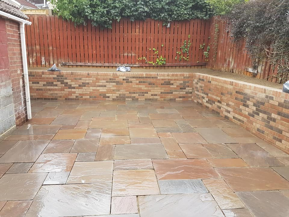patio install alongside stone wall
