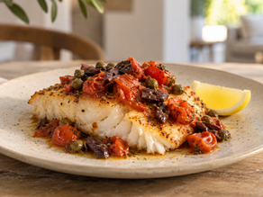 Overhead view of cod, cherry tomatoes, Kalamata olives, capers and lemon