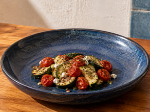Zucchini, cherry tomatoes, feta, garlic, oregano and parsley arranged in glass bowls