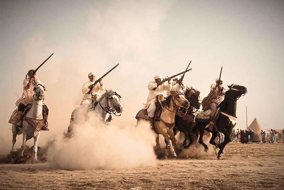 Traditional moussem. Riders in traditional attire charge on horses with rifles raised, creating dust clouds .