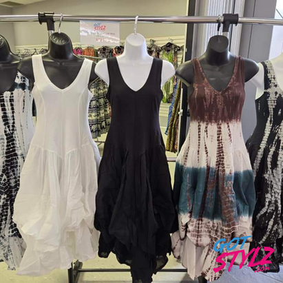 Three mannequins displaying dresses, with the center mannequin in a black sleeveless dress and the others in lighter colored dresses with patterns, in a retail setting. Got Stylz