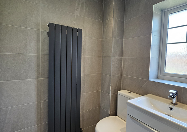 modern bathroom in Evesham with grey tiles wall mounted vanity and black radiator