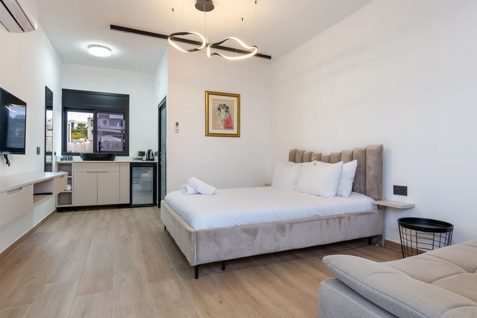 חדר שינה לבן מודרני עם מיטה זוגית, חדר קטן ונעים.