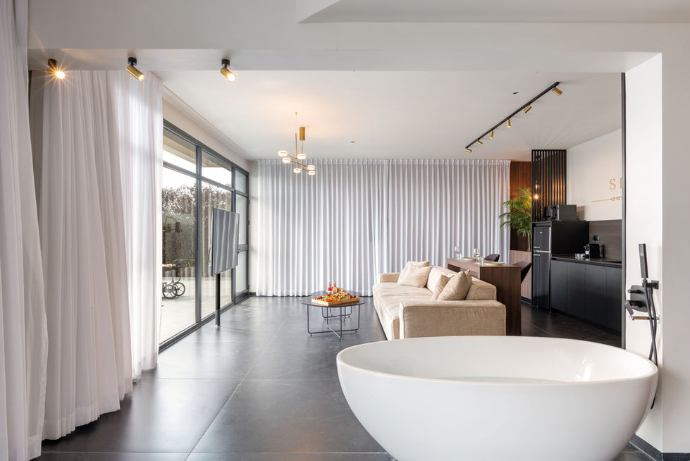 סלון מודרני לבן עם ספה בהירה, חלון גדול, פרטים עיצוביים.