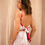 Thumbnail: Model wearing The Rosey Set – a two-piece outfit with red rose print on a pink background, featuring a crop top and wrap midi