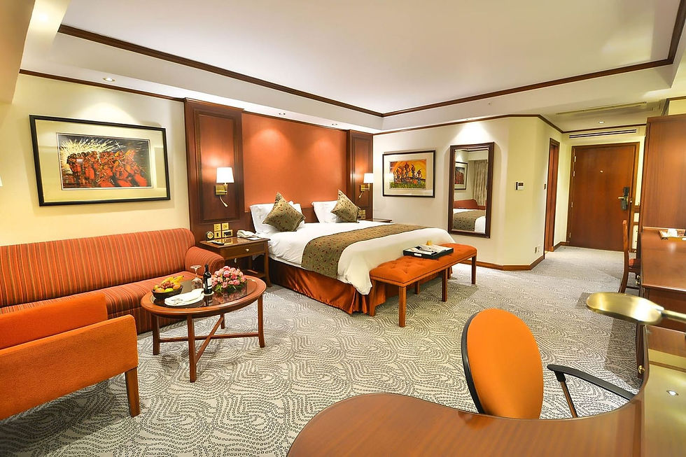 Luxurious hotel room with a large bed, seating area and artwork.