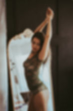 Woman poses in green lingerie by a mirror, intimate photography session