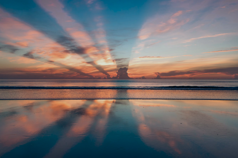 Sunrise with cloud strata and calm waters at the beach