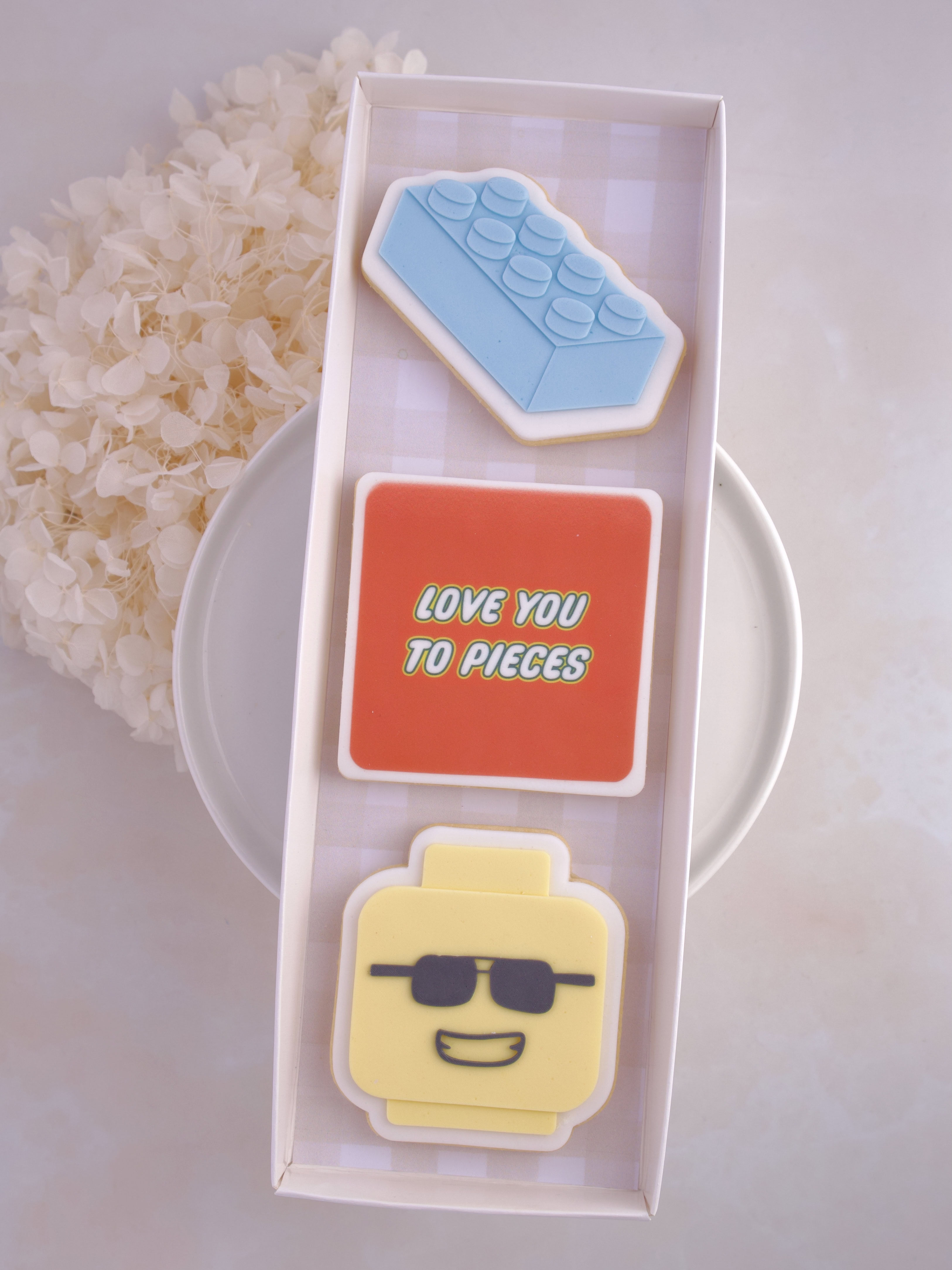 lego themed cookies brick mini-figure head and text that says love you to pieces