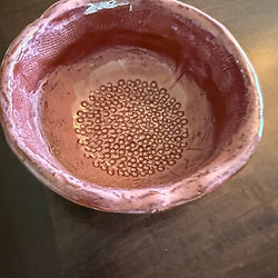 Pink handmade bowl with a dotted bottom decoration on a wooden table
