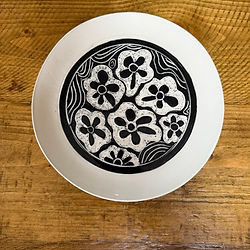 A plate in black with white sgraffito carving of abstract flowers