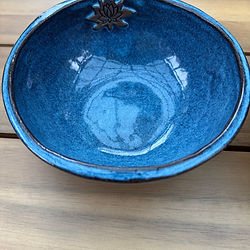 Blue handmade big salad bowl with a lotus flower decoration on a wooden table