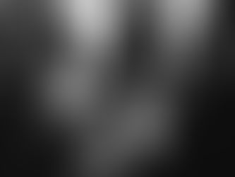 Person in bar holding phone displaying their bar loyalty app, bartender in white shirt smiling nearby. Dimly lit, lively atmosphere. Black and white.