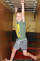 Boy hangs from monkey bars