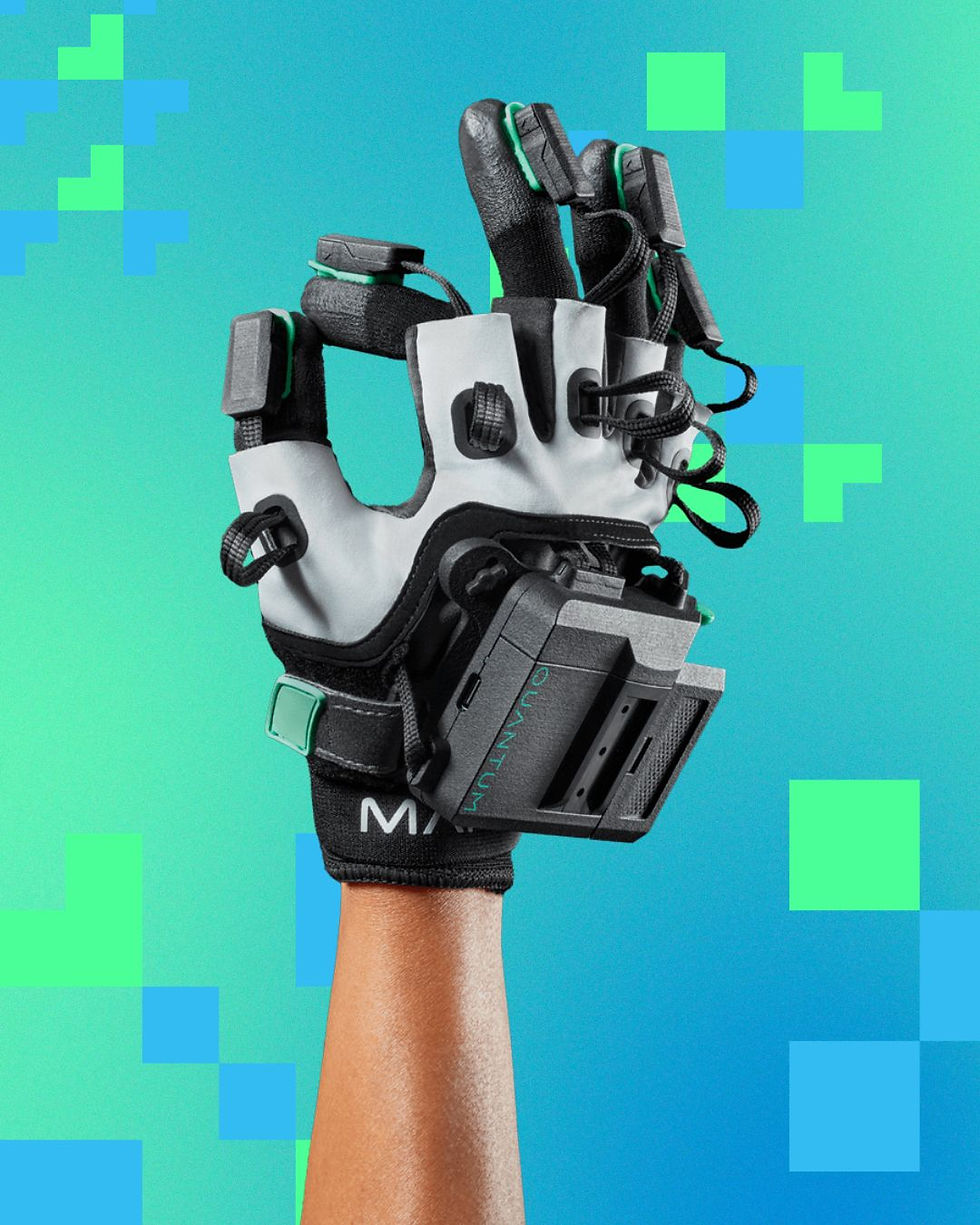 Arm wearing a Manus Quantum Metaglove with black and gray details, labeled "QUANTUM," on aqua background with pixelated green and blue squares.