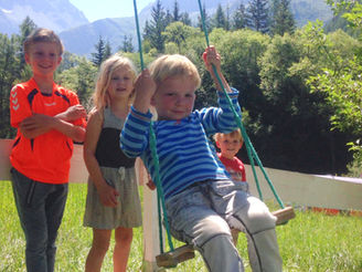 Enfants jouant à la balançoire au Camping des Lanchettes, montagnes en arrière-plan