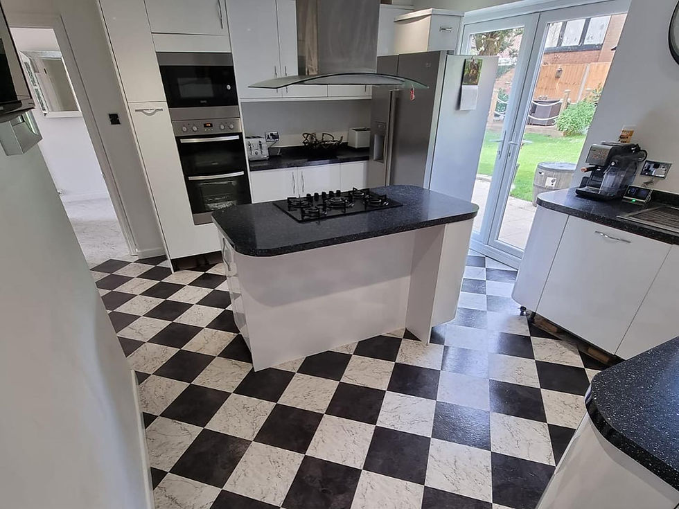 Modern kitchen with black and white checkered floor, white cabinets, and stainless steel appliances. Glass doors lead to a garden.