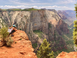 hiker taking picture off a cliff edge at Angels Landing in Utah
