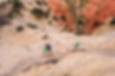 two individuals climbing accross a Zion rock face while on a via ferratta climbing tour at East Zion Resort.