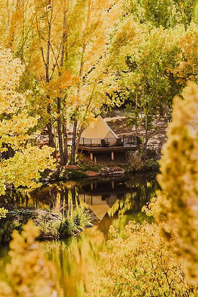 Glamping in Utah at Cave Lakes with a luxury tent on a private deck, surrounded by golden autumn trees and reflected in the lake.