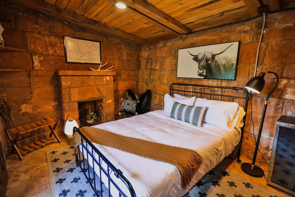 Stone House interior bedroom with bed, fireplace, and wood ceiling.