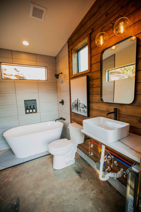 Private, modern bathhouse interior with shower, sink, and mirror.