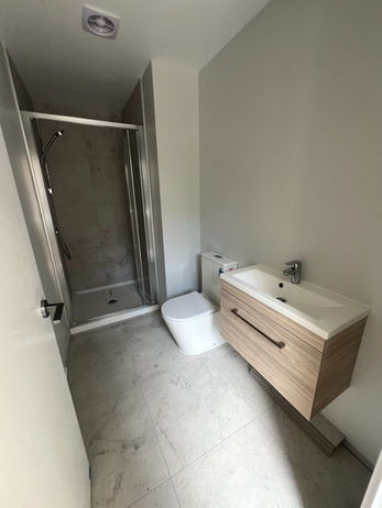 Bathroom featuring a shower, toilet and sink.
