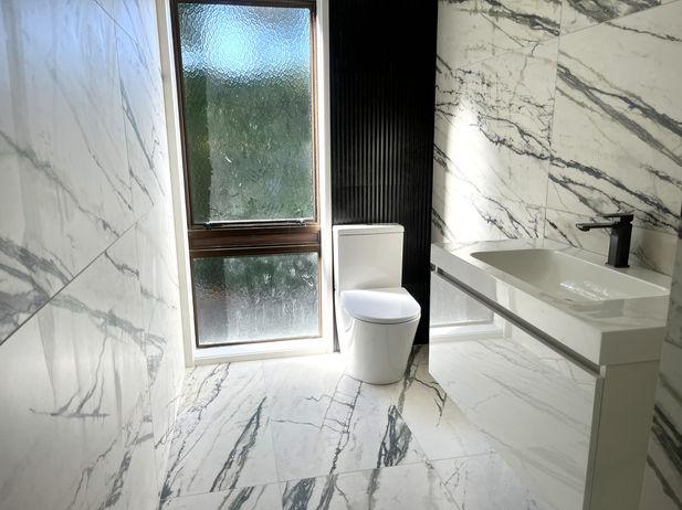 Renovated bathroom featuring a toilet and wash basin.