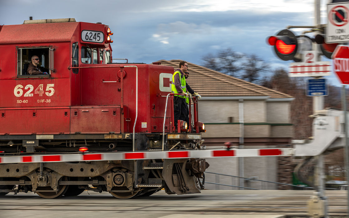 Red train at railway crossing with crew on side