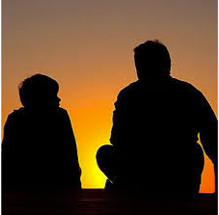 Silhouette from the back of a dad and his son with the colors of a sunset in the background