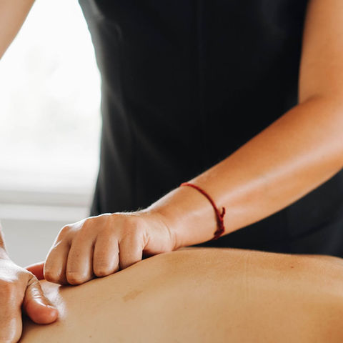 Close view of a therapist providing a back massage; illustrative stock photograph