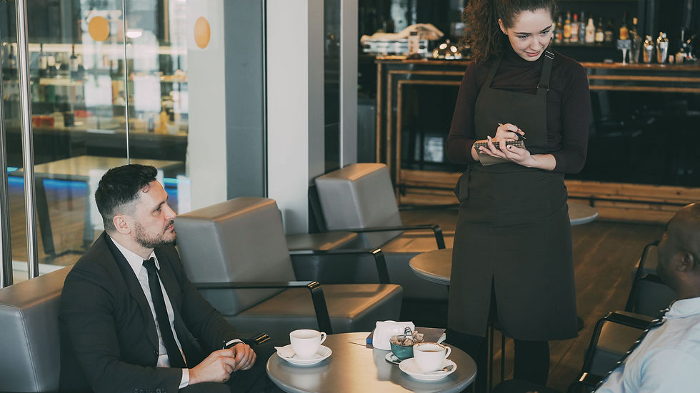 Professional service conversation between customers and a team member in a modern cafe