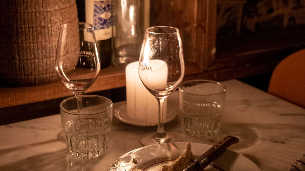 A candlelit dining table set with wine glasses