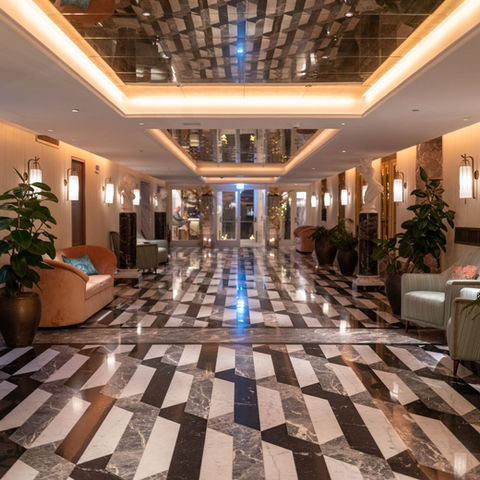 A polished hotel corridor with decorative arches and plants; illustrative stock photograph
