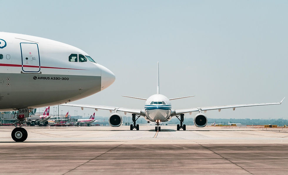 Two airplanes on a runway, one taxiing towards the camera. Visible "Airbus A330-300" text. Clear sky, airport setting with red vehicles.