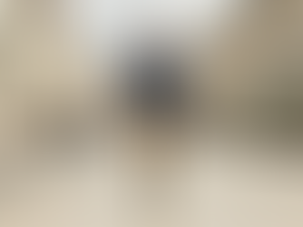 Man in a UPF fedora hat walks down a sunny city street with a tram on the right. He's wearing a navy top, tan pants, and carrying a black bag.